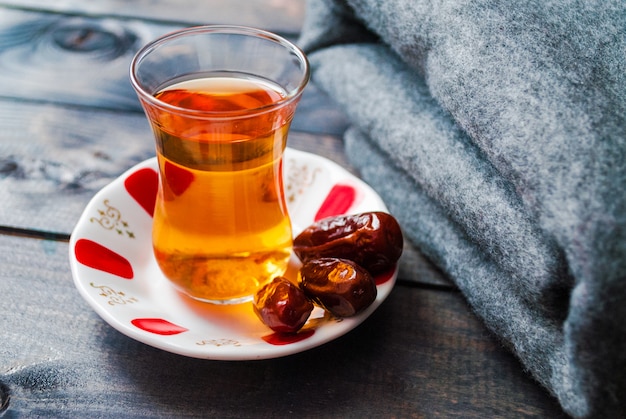 A glass of black tea and dates on a saucer