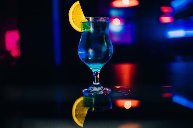 Glass of blue alcohol cocktail Martini with a slice of orange party at bar