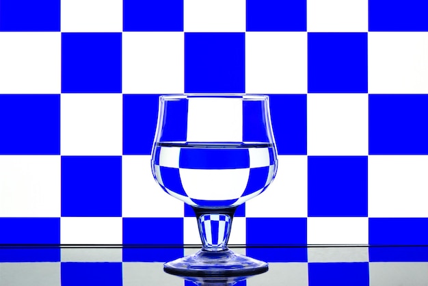 Glass on a blue and white background with a reflection on the table.