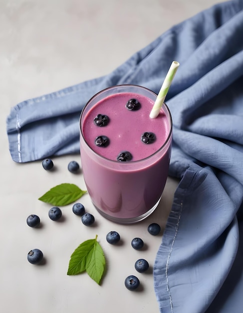 Photo a glass of blueberries and a straw is next to a blue cloth