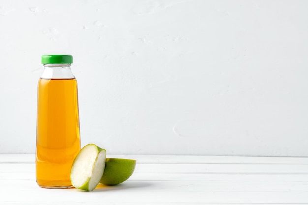 Glass bottle of apple juice with apple fruit on white background