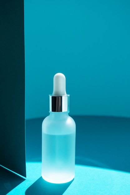 Glass bottle essential collagen anti-aging serum with vitamin A and vitamin E on blue paper background.