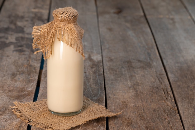 Glass bottle of milk on old wooden background close up