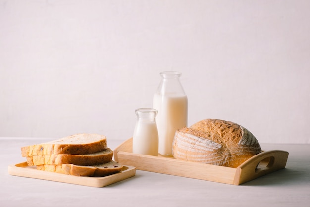 Glass bottle of milk with bread on wooden tray isolated on white background for food and healthy concept. with copy space for text