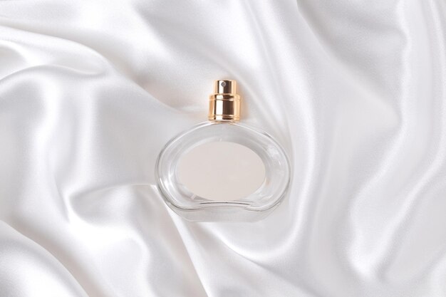 Glass bottle of perfume on a white silk the concept of expensive perfume and cosmetics