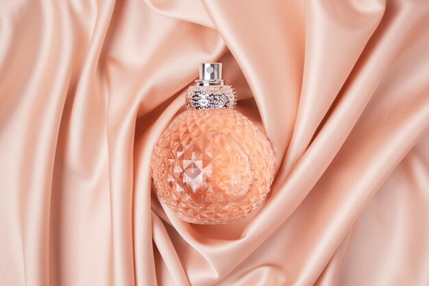 Glass bottle of perfume without a lid on a background of pink silk the concept of expensive perfume and cosmetics