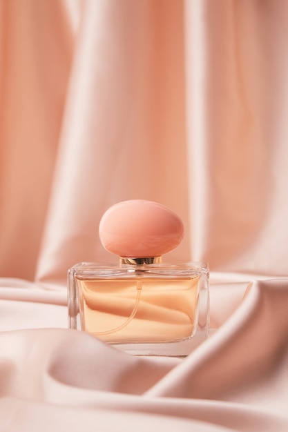 Glass bottle of perfume without a lid on a background of pink silk the concept of expensive perfume and cosmetics