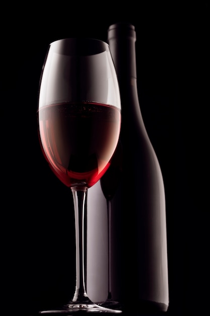 Glass and bottle of red wine on a black surface