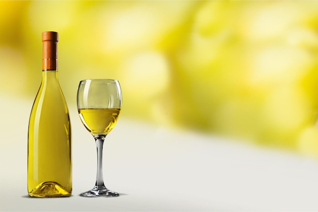 Glass and bottle of white wine on background