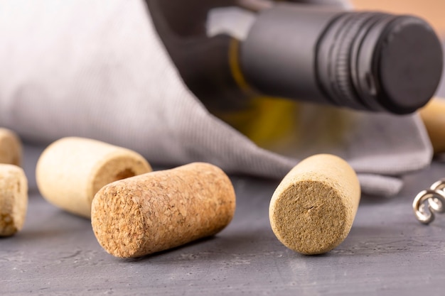 Glass bottle of wine with corks on wooden table