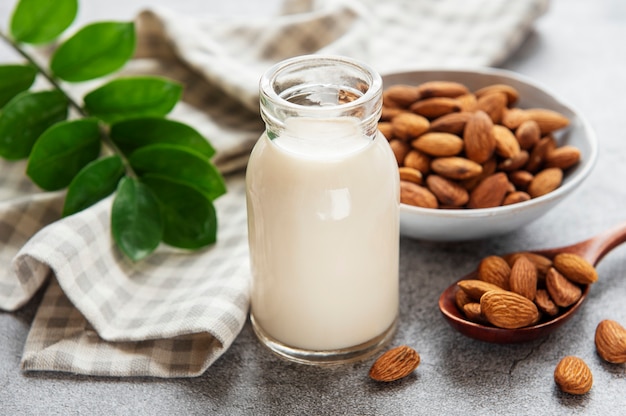 Glass bottle with almond milk and almonds on the table