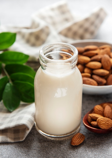 Glass bottle with almond milk and almonds on the table