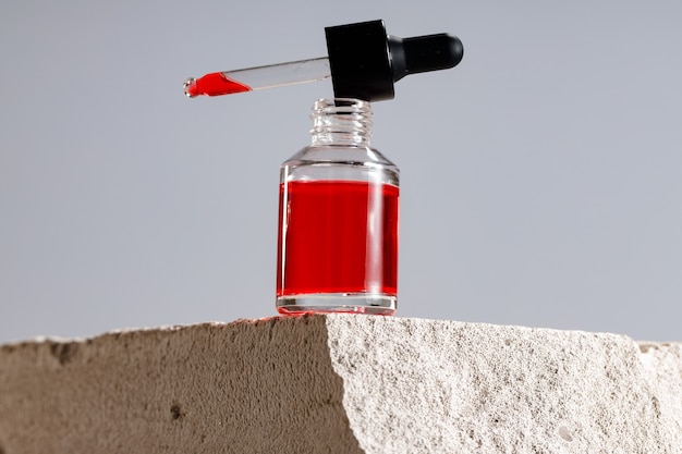 Glass bottle with cosmetic oil on gray cinder block