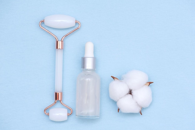 Glass bottle with serum or essential oil and face massage roller and cotton thread