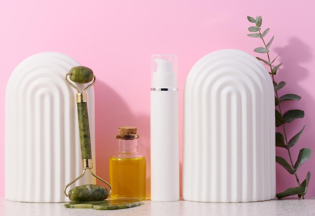 Glass bottle with yellow massage oil and stone hand massager on pink background alternative medicine