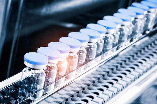 Glass bottles in production in the tray of an automatic liquid dispenser; a line for filling medicines against bacteria and viruses; antibiotics and vaccines.