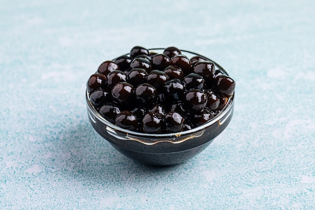 Glass bowl of black tapioca pearl bubbles on the blue background