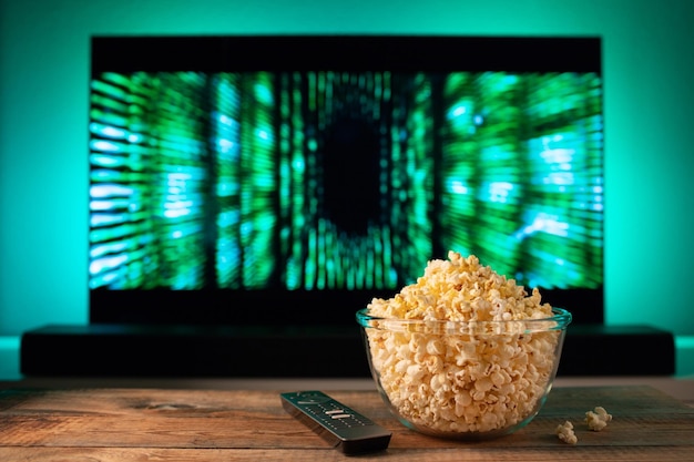 A glass bowl of popcorn and remote control in the background the tv works