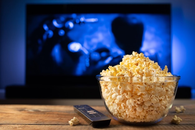 A glass bowl of popcorn and remote control in the background the tv works