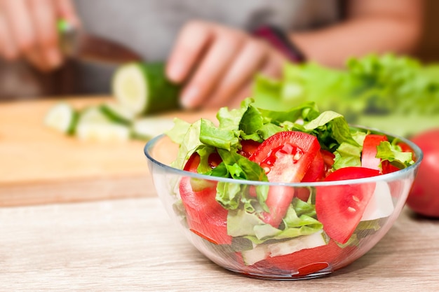 A glass bowl with a fresh vegetable salad in the foreground