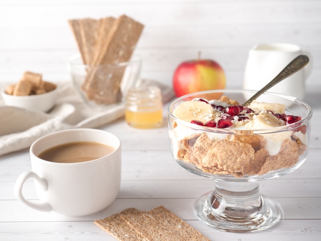 Glass bowl with muesli and yogurt with banana, pomegranate seeds.