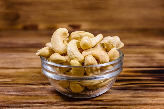 Glass bowl with raw cashew nuts on a wooden table