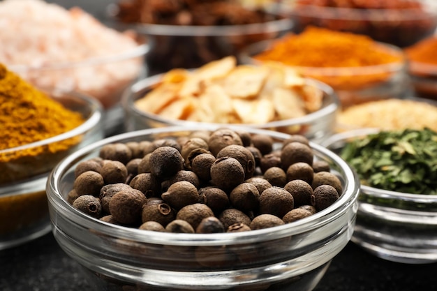 Glass bowls with different spices on grey textured table closeup