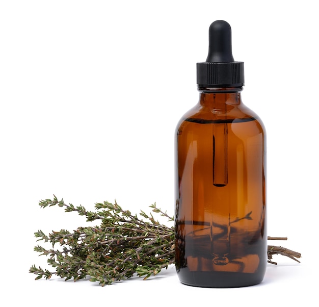 A glass brown bottle with a pipette and a branch of cumin on a white isolated background a container for oils and essences