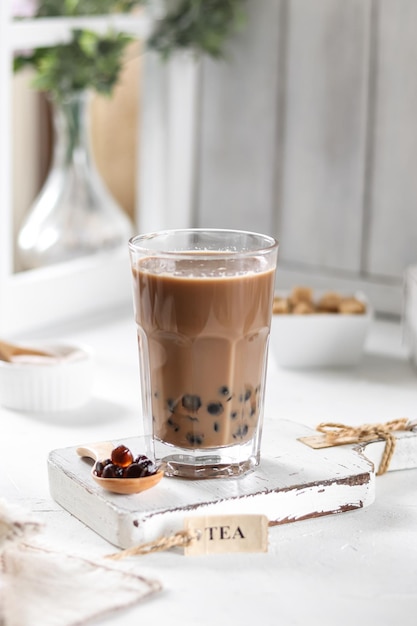 A glass of bubble tea with a bowl of peanut butter next to it.