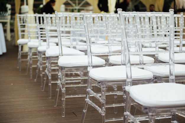 Glass chairs stand in a row in a beautiful wedding outing ceremony