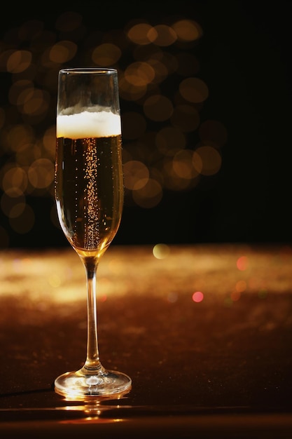 Glass of champagne with golden bubbles on table against blurred background Space for text