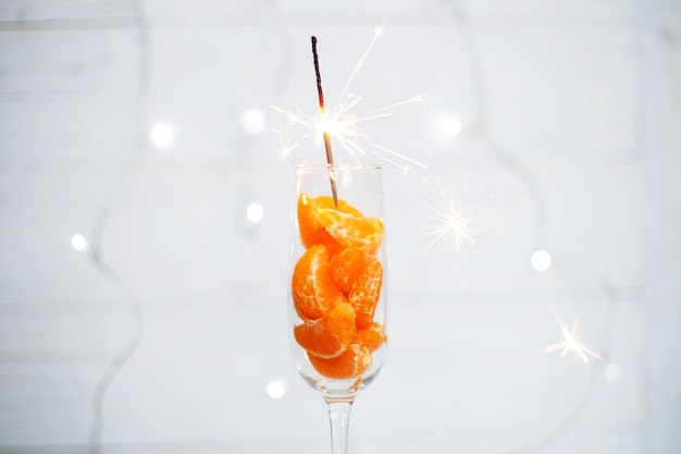 A glass of champagne with tangerines and a burning sparkler