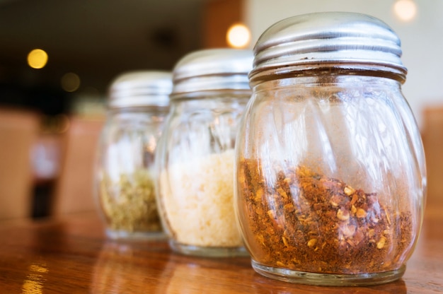 Glass of cheese salt and pepper shakers on wooden table in restaurant