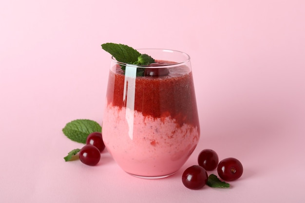 Glass of cherry smoothie and ingredients on blue background