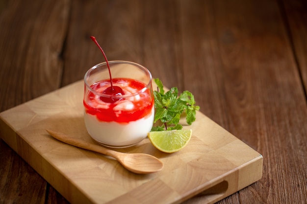 Glass of Cherry yogurt on a brown wood table.