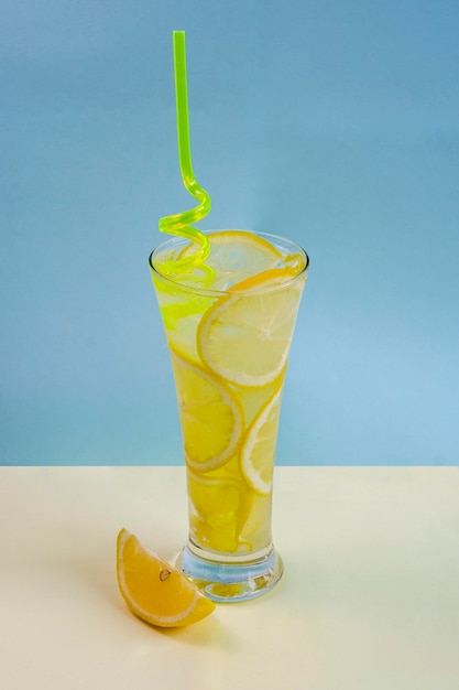 A glass of chilled lemonade iced water and lemon soft drink and lemon on a blue background