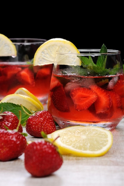 A glass of chilled strawberry lemonade mint leaves a slice of lemon with ice