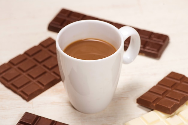 Glass of chocolate milk and bars chocolates  on table