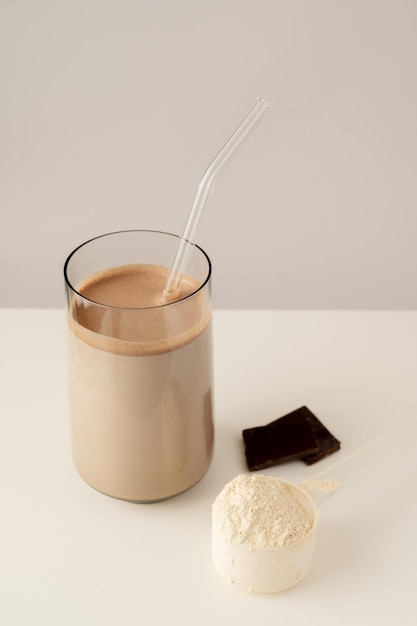 A glass of chocolate milk with a straw pouring into it.