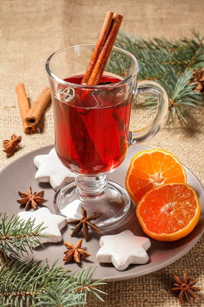 Glass of Christmas mulled wine with spices and cookies orange on plate