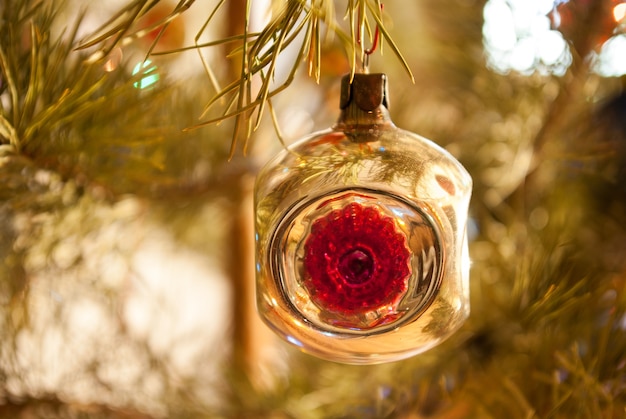 Glass Christmas tree decoration on a background of a Christmas tree with lights