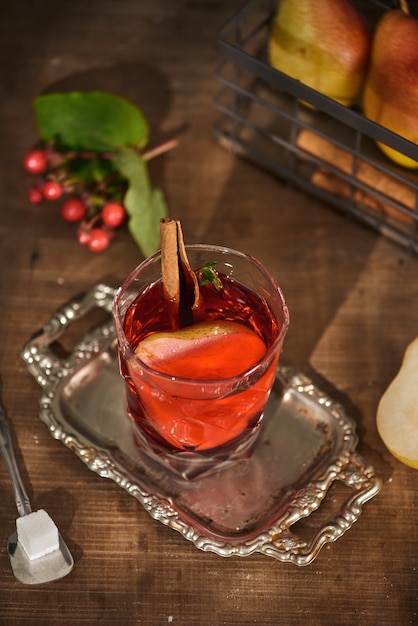 Glass of Cider pear cocktail or lemonade, cinnamon sticks, anise stars on wooden surface.