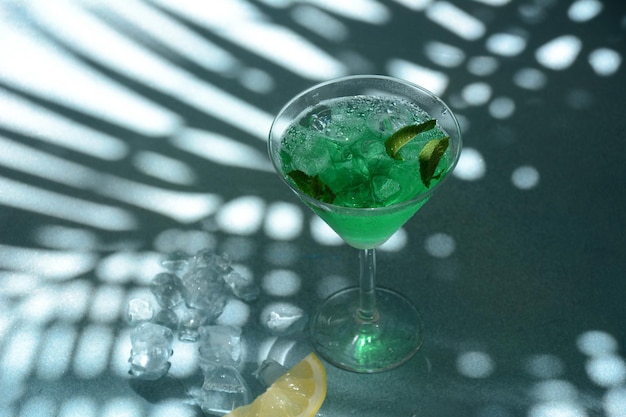 Glass of cocktail green fairy with lemon and mint leaves Sweet refreshing mint liqueur with ice and absinthe rum Ice cubes and Vodka