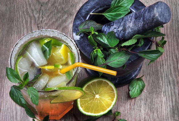 A glass of cocktail with a straw and mint.