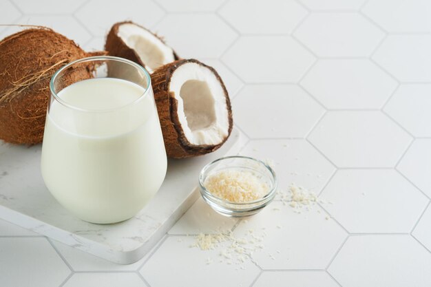 Glass of coconut milk and coconut close up on a white background with space for text Coconut vegan milk non dairy or Dairy free milk concept Healthy vegan food