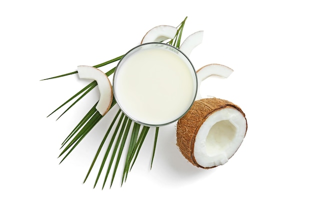 Glass of coconut milk and nuts on white background top view