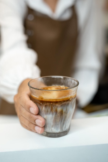 A glass of coffee with a person holding it