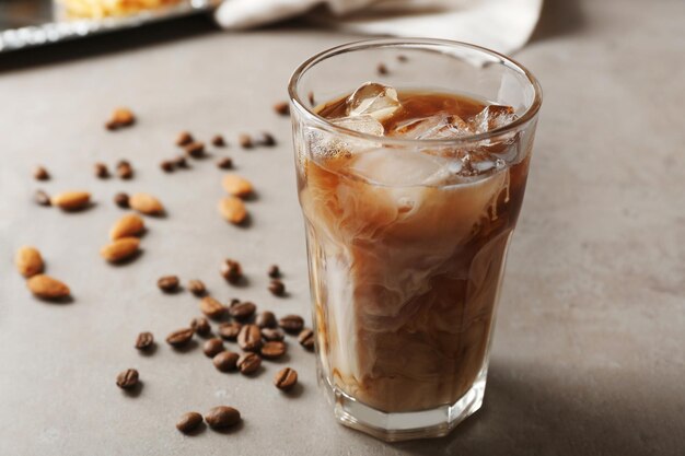 Glass of cold coffee with beans and nuts on table