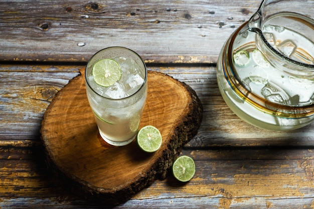 Glass of cold lemonade on wooden table. Ice cold drink.