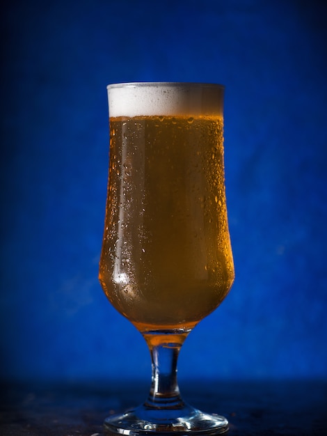 A glass of cold light beer lager on a dark surface